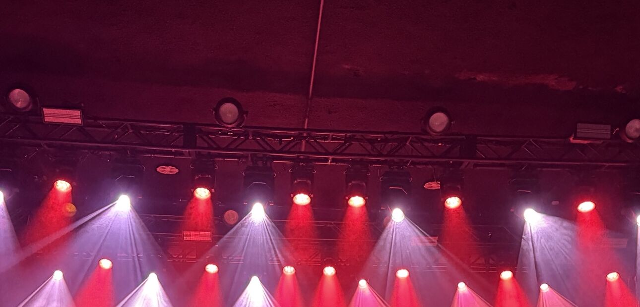 The lighting rig over the stage, red and white beams in the haze.