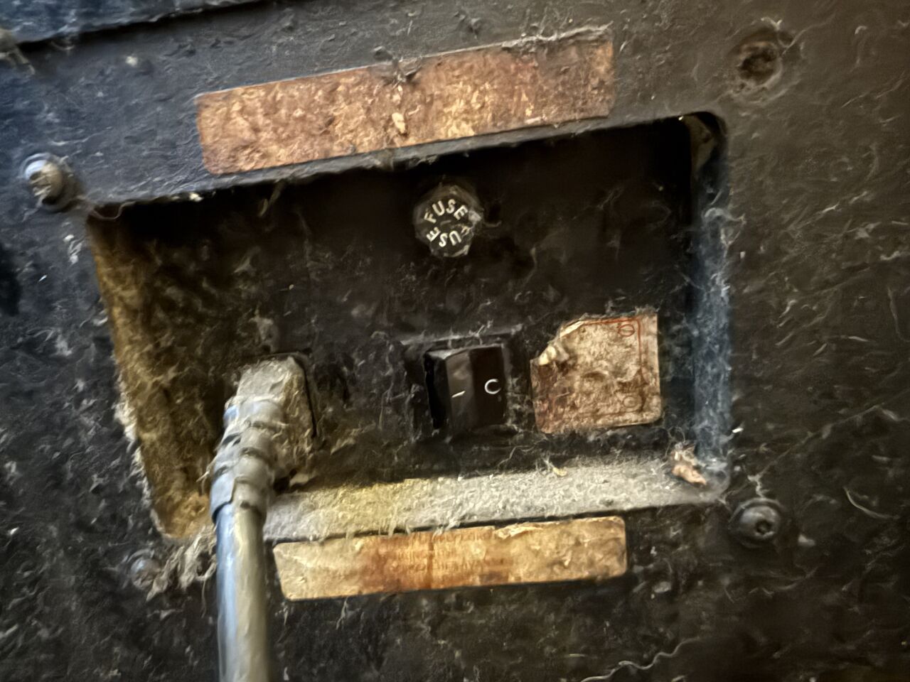 The back of an amp: fuse holder and power switch, thick with dust and old tape.